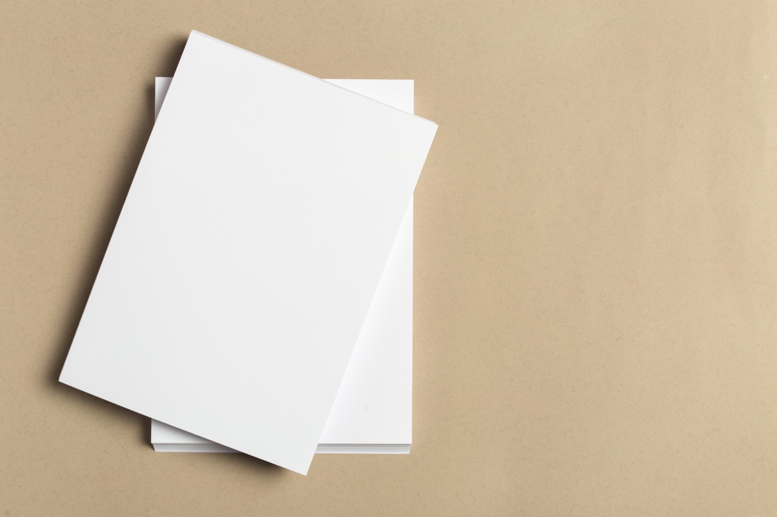Blank paper flyers arranged on a cream tabletop