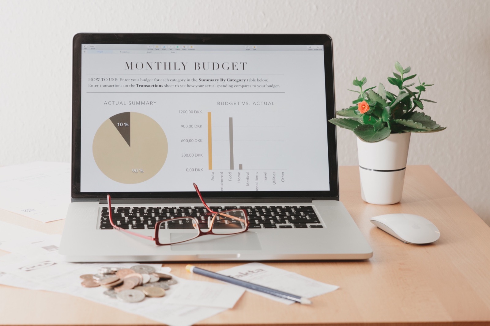 A laptop displaying a monthly budget beside notes and a potted plant
